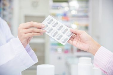 Hastaya ilaç veren eczacı ellere yakın 