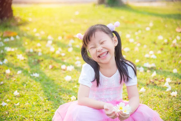 สาวน้อยนั่งและยิ้มบนสนามหญ้า — ภาพถ่ายสต็อก