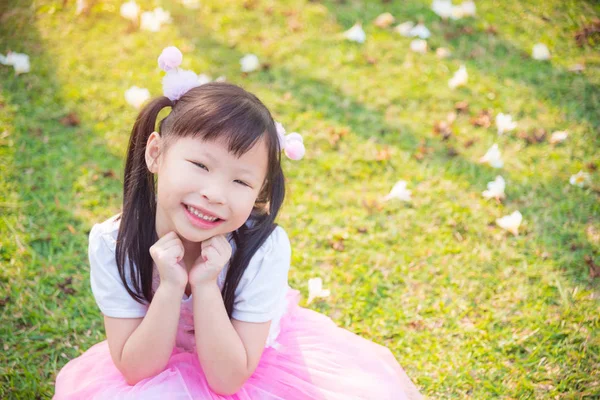 Little  girl sitting and smiles on grass field — Stock Photo, Image