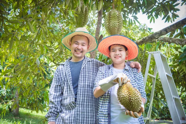 Agricultor e filho segurando Durian e sorrir feliz em seu jardim . — Fotografia de Stock
