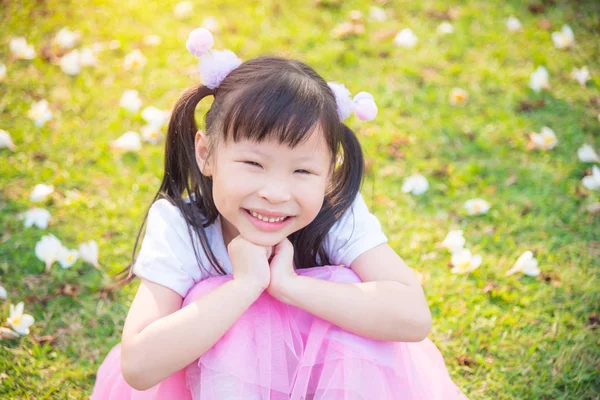 Little girl sitting and smiles on grass field — Stock Photo, Image