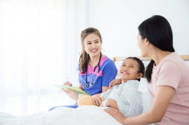 Genç asyalı doktor kız hasta ve anne ile gülümseyen 
