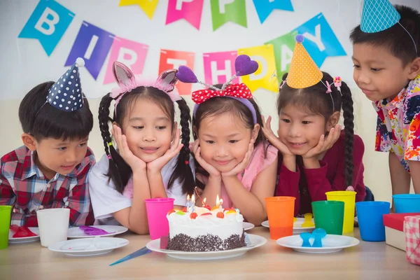 Grupa azjatyckich dzieci patrząc na świeczkę na ciasto na przyjęcie urodzinowe — Zdjęcie stockowe