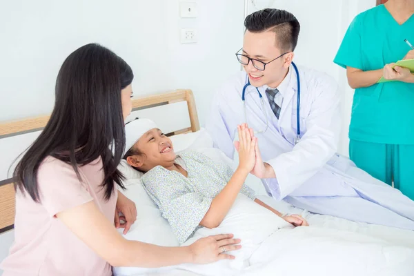 Joven asiático macho médico tocando la mano con una chica paciente que se acuesta en la cama — Foto de Stock