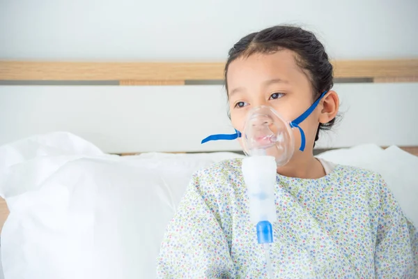 Sick girl sitting on bed with oxygen mask — Stock Photo, Image