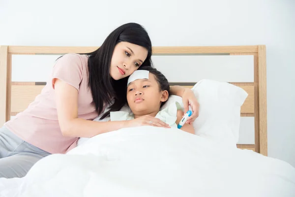 Madre usando termómetro digital comprobando la temperatura de su hija — Foto de Stock