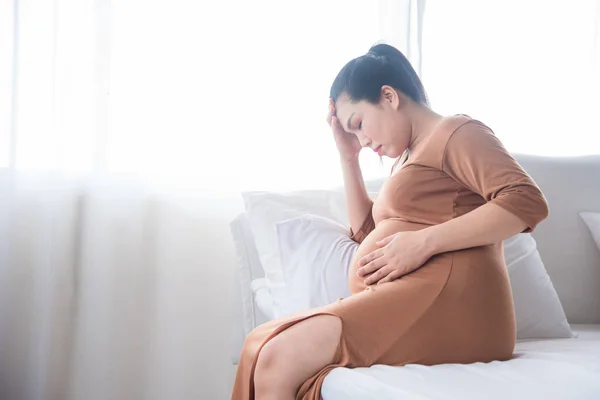 Donna incinta di mezza età seduta sul letto, con mal di testa da ipertensione — Foto Stock