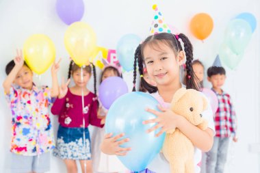 Küçük güzel kız mavi balon tutan ve doğum günü partisinde gülümsüyor