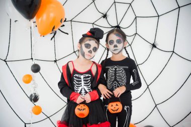 Odada duran makyaj ile iskelet kostümlü iki kız