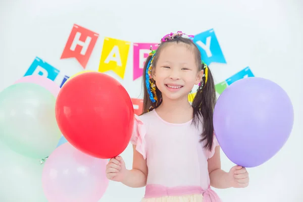 Mała dziewczynka trzyma balony i uśmiechnięta w jej urodziny — Zdjęcie stockowe