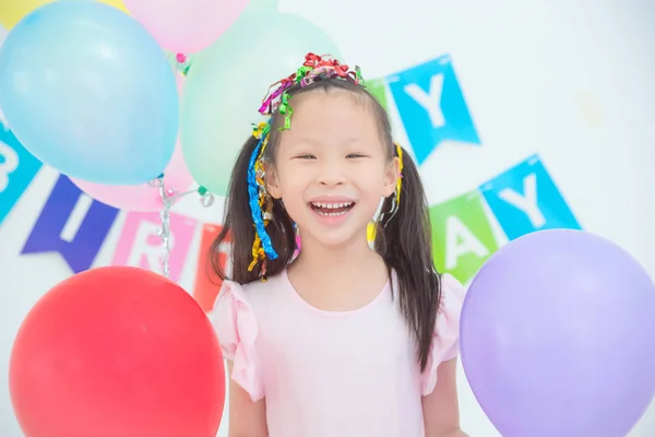Mała dziewczynka trzyma balony i uśmiechnięta w jej urodziny — Zdjęcie stockowe