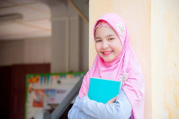 Gadis muslim cantik memegang buku dan tersenyum — Stok Foto