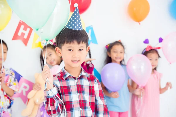 Trochę Asian chłopak trzyma balony i uśmiechy w urodziny impreza — Zdjęcie stockowe