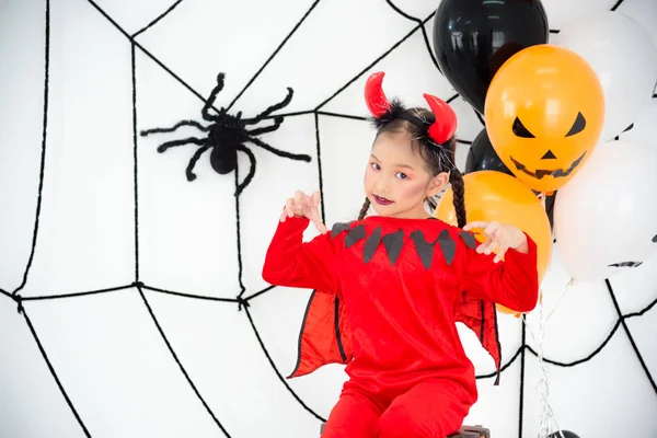 Bella ragazza in costume diavolo rosso con corno seduto in camera — Foto Stock