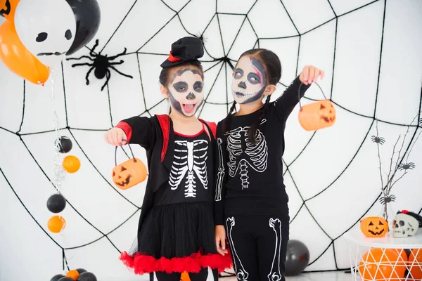 Two girls in skeleton costume with makeup standing in room