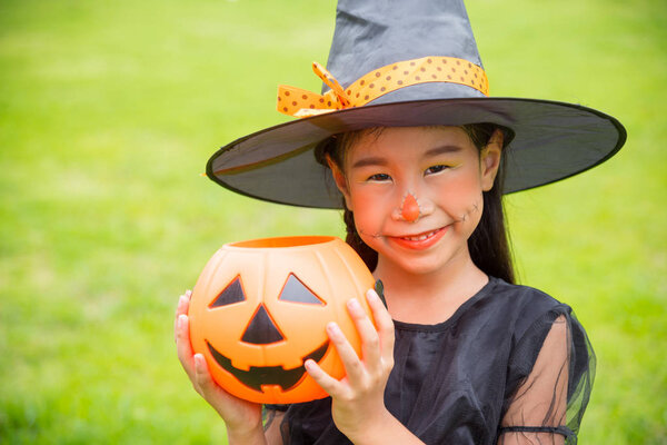 Little asian girl in witch costume celebrate Halloween outdoor 