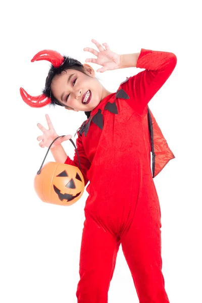 Маленька дівчинка в червоному костюмі диявола стоїть і тримає відро з гарбуза на Хеллоуїн — стокове фото