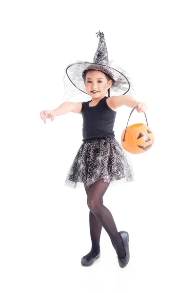 Longitud completa de la niña en traje de bruja de pie y la celebración de cubo de calabaza de Halloween — Foto de Stock