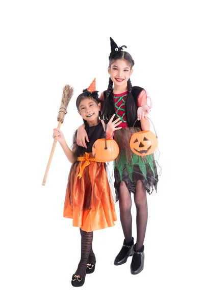 Comprimento total de duas meninas em traje de bruxa segurando balde de abóbora halloween e sorriso — Fotografia de Stock