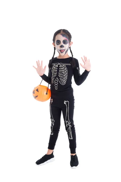 Longitud completa de la muchacha en traje del esqueleto que sostiene cubo de calabaza de Halloween, de pie y sonrisas — Foto de Stock