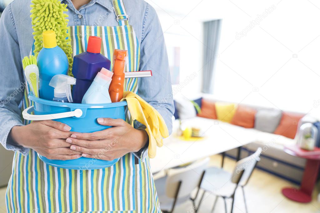 woman with cleaning equipment ready to clean house on living room background
