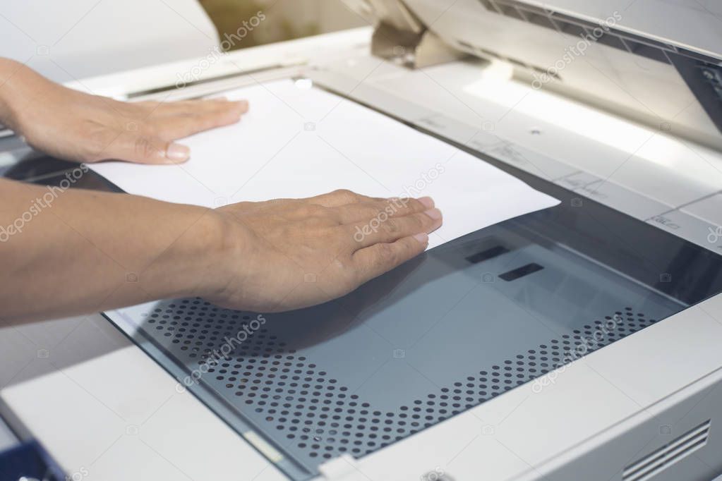 woman hands putting a sheet of paper into a copying device