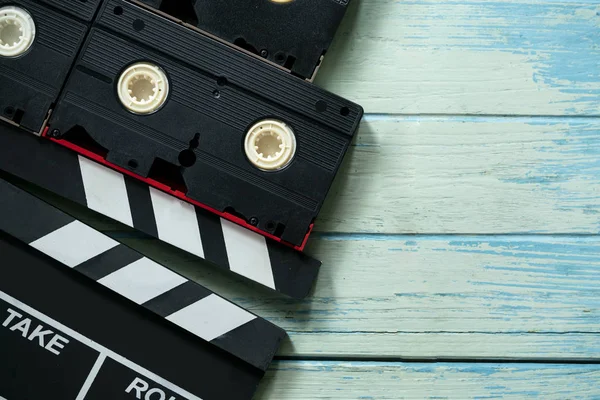 movie clapper and video cassette tapes on wood table ; film, cinema and video photography concept