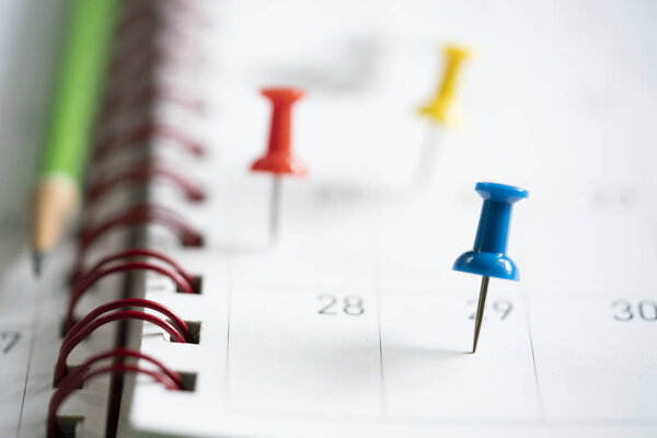 Закрытие булавки и карандаша на календаре, планирование деловой встречи или планирование поездок на столе
 