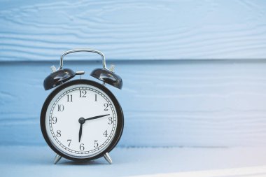 Ahşap masa üzerindeki çalar saat mavi arkaplanlı, antika tarzı