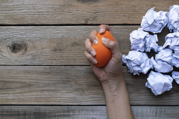 Mano de una mujer apretando una bola de estrés con papel arrugado en t — Foto de Stock