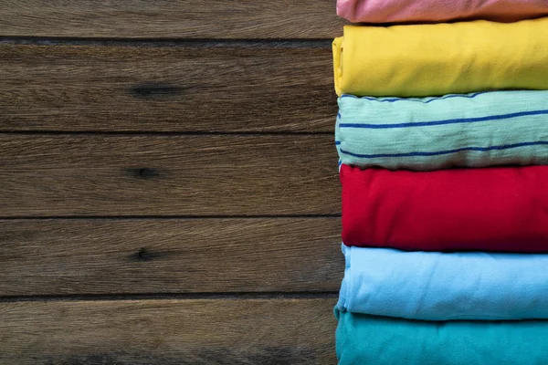 Gros plan de vêtements colorés roulés sur fond de table en bois — Photo