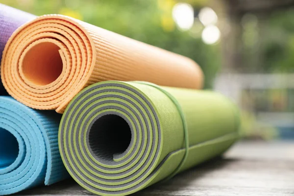 Primer plano de colorido estera de yoga sobre la mesa, deporte y co saludable —  Fotos de Stock