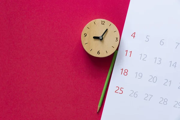 Primo piano del calendario, orologio e matita sul backgrou tavolo rosso — Foto Stock