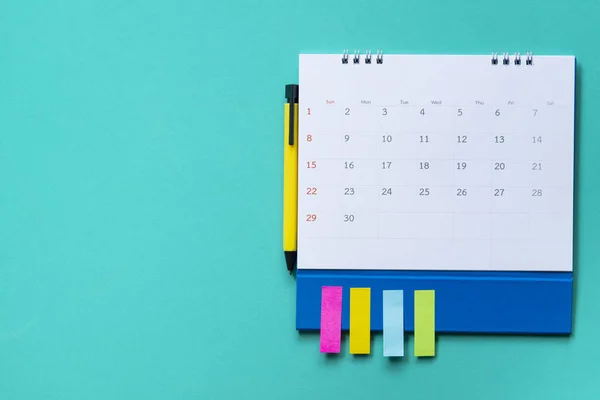 Закрыть календарь и ручку на зеленом фоне стола, план — стоковое фото