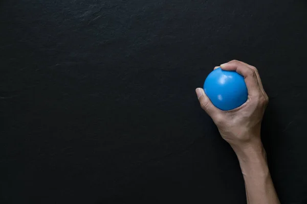 woman holding a stress ball in her hand on black background