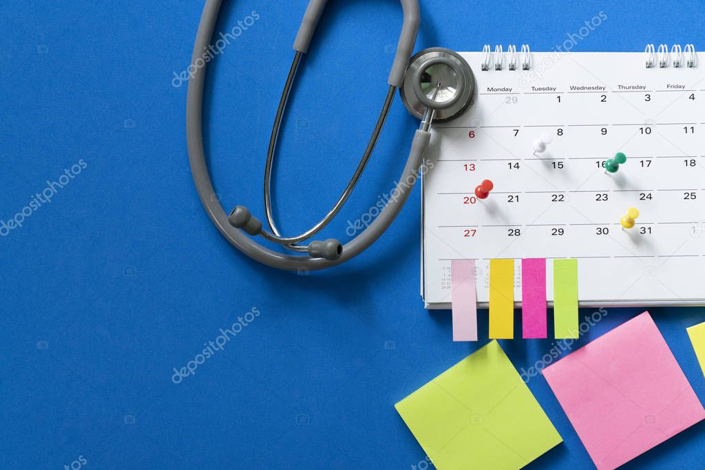 Top view of stethoscope and calendar on the blue background, sch