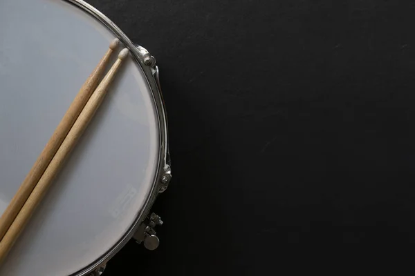 Drumstick en drum op zwarte tafel achtergrond, Top View, muziek c — Stockfoto
