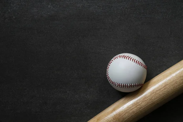 Batte de baseball et de baseball sur fond de table noire, gros plan — Photo