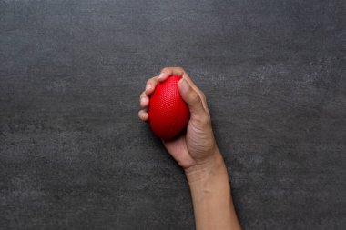 Kadın eli siyah masa arkasında stres topu tutuyor. 