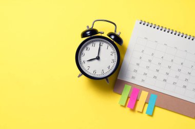 sarı masadaki takvim ve alarmın kapatılması, iş toplantısı ya da seyahat planlama konsepti