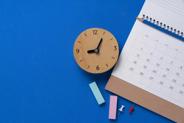 在蓝色桌子背景 商务会议规划或旅行规划概念上关闭日历和闹钟 — 图库照片