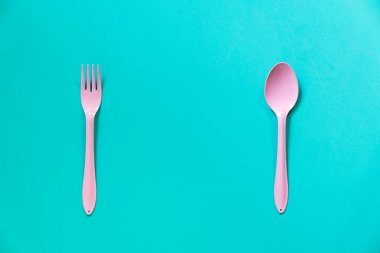 Yeşil masa arkasında pembe kaşık ve çatal, yemek ve sağlıklı konsept.