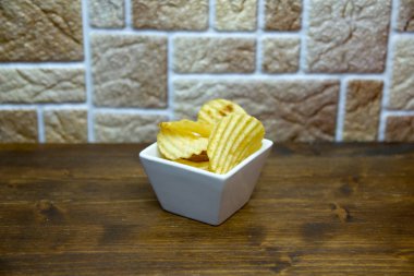 Yukarıdan izlendi ahşap bir masa kare kase içinde oluklu cips