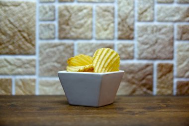 Ahşap bir masa kare kase içinde oluklu cips