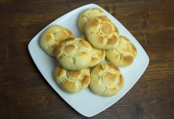 Yukarıda görülen ve yakın ahşap bir masa üzerinde bir tabakta ekmek