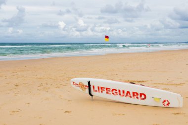 Gold Coast, Avustralya - 5 Ocak 2015: altın kum ile bulutlu bir günde Surfers Paradise plajında sörf tahtası cankurtaran ve Pasifik Okyanusu yukarıda gökyüzü kaplı