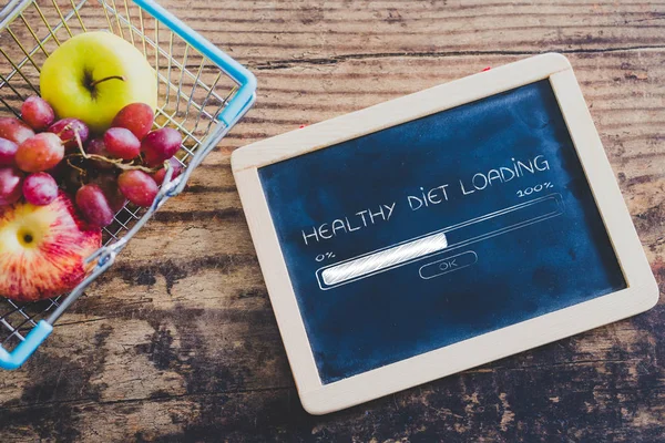 blackboard next to shopping cart with healthy diet loading text and progress bar, on wooden table