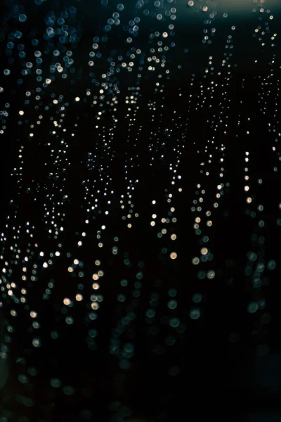 ボケのライトは 懐中電灯に照らされた窓に雨粒が作られた背景を抽象化またはテクスチャのショット — ストック写真
