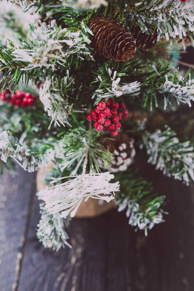 detail of small Christmas tree with snow mistletoe and pine cone decorations, cozy festive winter holidays feeling