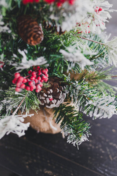 Christmas tree with pine cones and mistletoes berries and hints of snow on the branches, cozy festive winter holidays feeling
